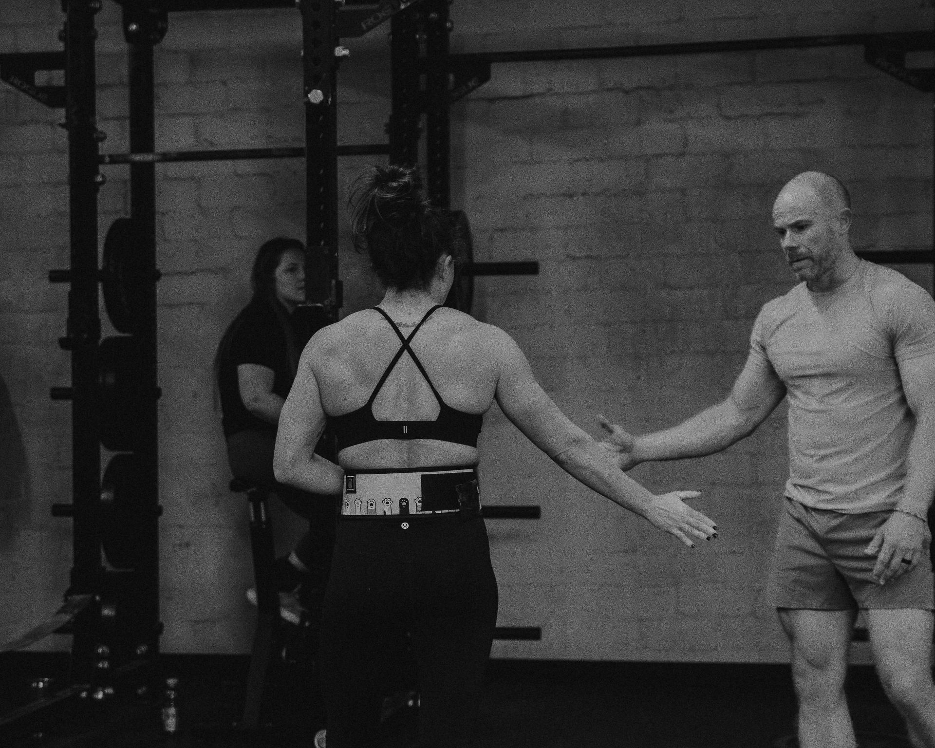 Two people meeting hands after a lift at a WLF Club training event.