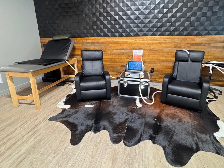 The recovery room at WLF Club, with two recliners, the PEMF unit between them, and an acoustic wall.