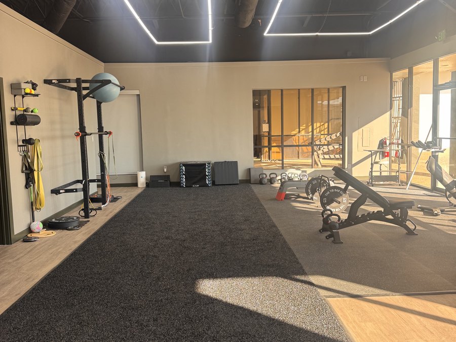 The strength floor at WLF Club, with a squat rack, kettlebells, plyo boxes, and bands on the wall.