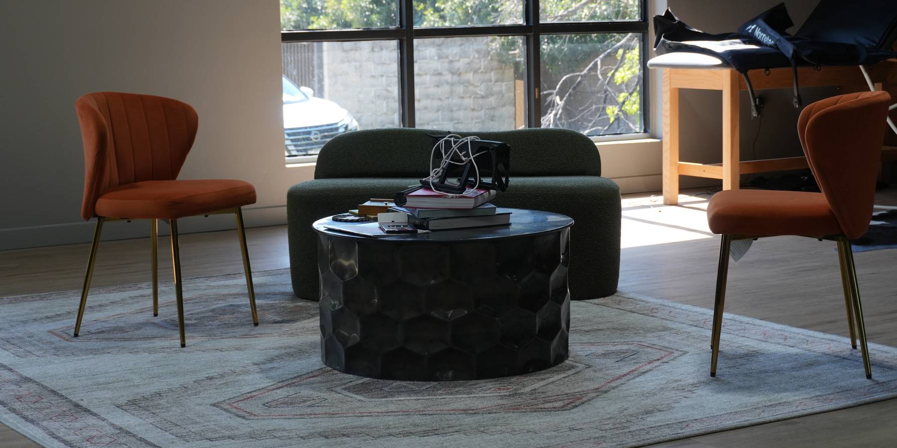 The lounge inside WLF Club in Fort Worth: two upholstered chairs facing a low round table and a green sofa, in front of a wall of windows.