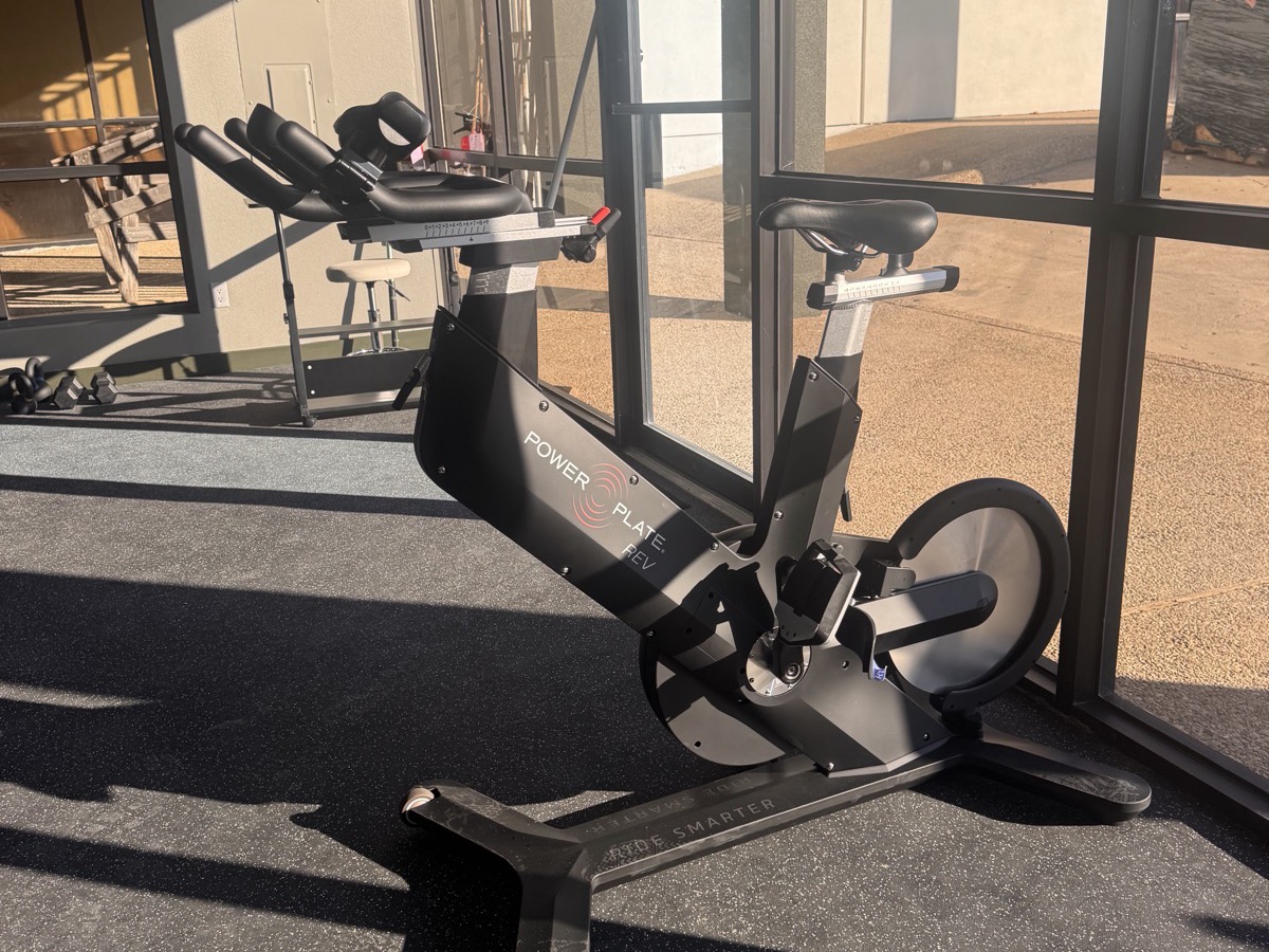 The Power Plate REV spin bike in front of the training room windows at WLF Club.