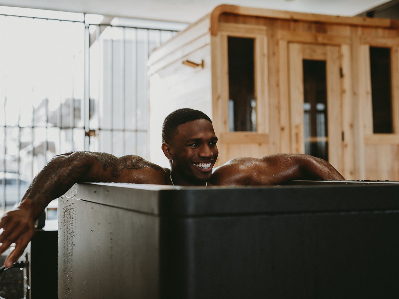 A WLF member resting in the cold plunge, the cedar sauna behind him.