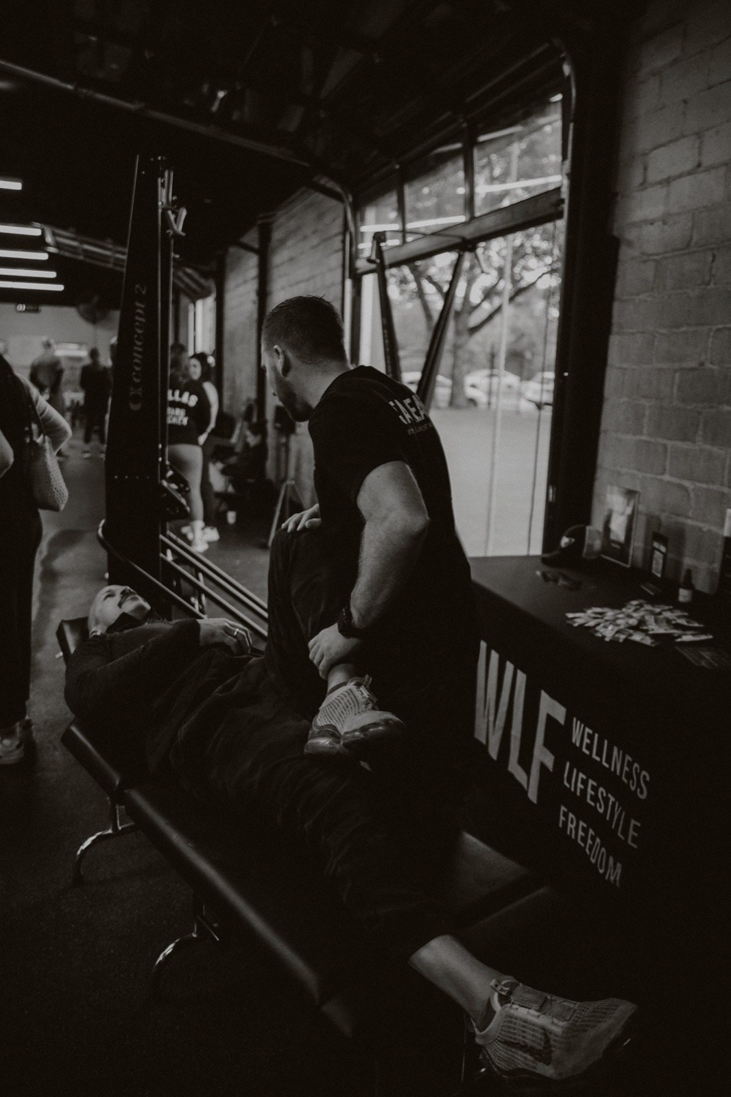 Dr. Colton Purscell working hands-on with a client on the treatment table beside a WLF banner.